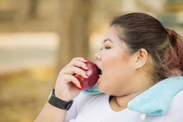 Mujer con sobrepeso comiendo manzana fresca después del ejercicio — Foto de Stock
