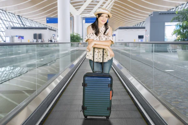 Woman standing on escalator with suitcase — Stock Photo, Image