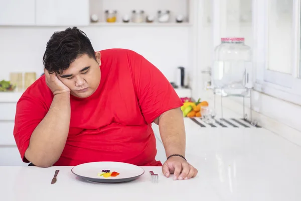 Giovane uomo grasso sembra annoiato di mangiare insalata — Foto Stock