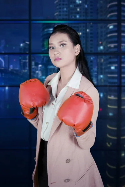 Angry businesswoman wears boxing gloves in office — Stock Photo, Image