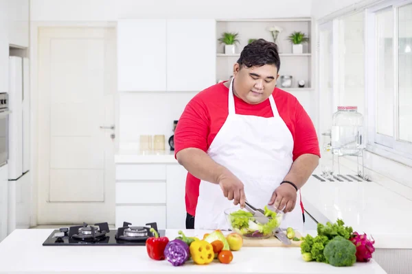 Młody tłuszcz człowiek mieszania miskę świeżych sałatek — Zdjęcie stockowe