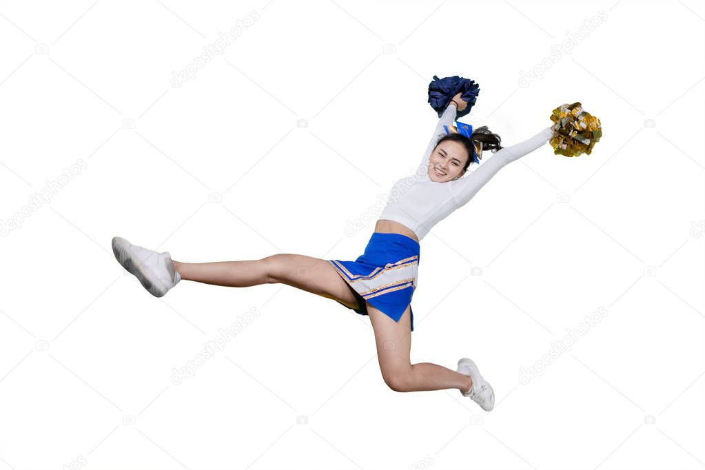 Happy cheerleader girl lifting pom poms on studio