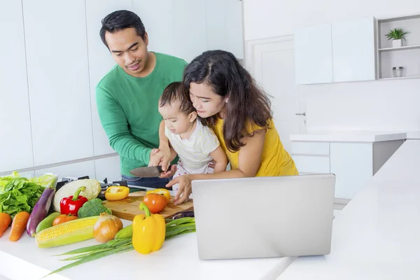 Menina aprende a cortar legumes com os pais — Fotografia de Stock