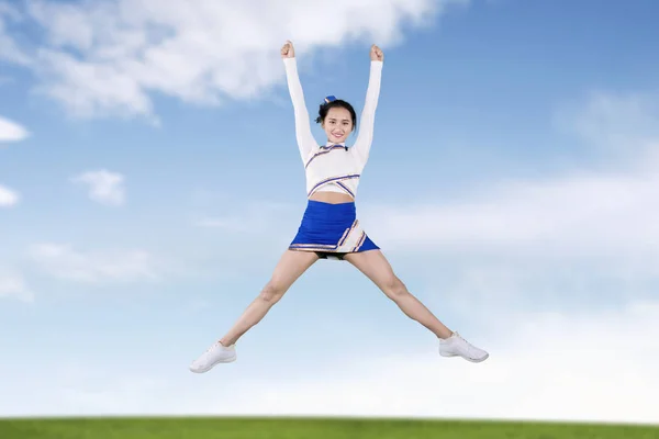 Cheerleader girl jumping in the meadow — Stock Photo, Image