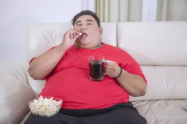 L'uomo in sovrappeso mangia popcorn e bevande cola fredda — Foto Stock