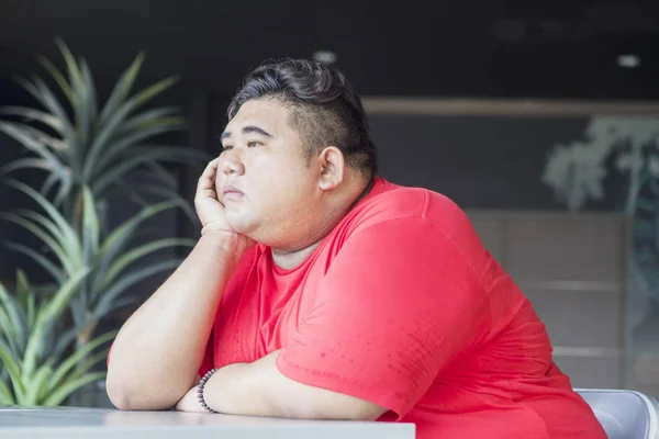 Homem com excesso de peso parece pensativo na cadeira — Fotografia de Stock