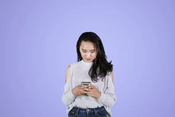 Pretty girl texting on a mobile phone in studio — Stock Photo, Image