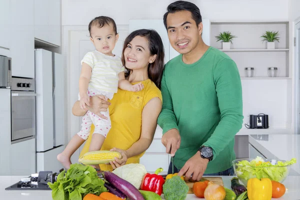 Улыбающаяся семья готовит овощи на кухне — стоковое фото