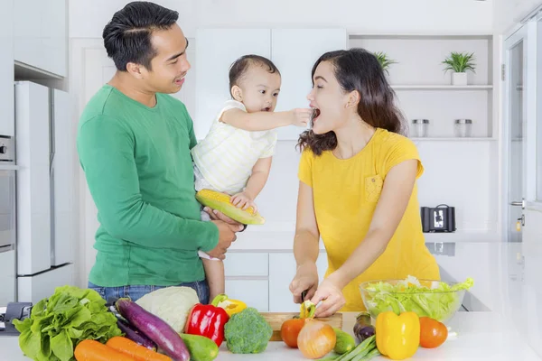 Молодая семья делает овощной салат на кухне — стоковое фото