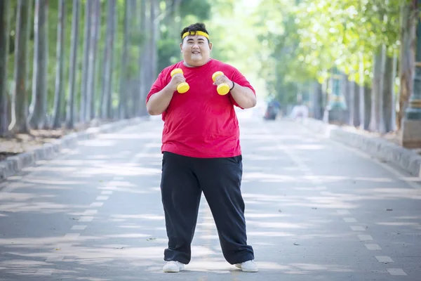 年轻的胖男人用哑铃锻炼 — 图库照片