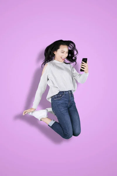 Молода жінка використовує телефон з щасливим виразом — стокове фото