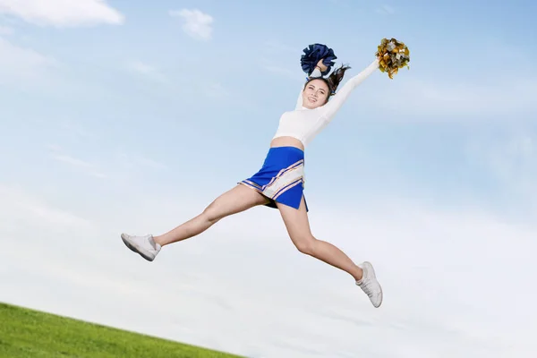 Pretty cheerleader jumping in the meadow — Stock Photo, Image