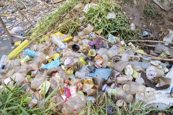 Vários montes de resíduos de plástico à beira do rio — Fotografia de Stock