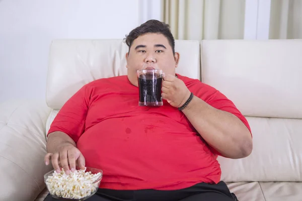 Jeune homme gras regarder la télévision avec du cola et du pop-corn — Photo