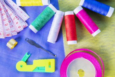 İpek kumaş üzerinde dikiş aletleri ile renkli iplikler