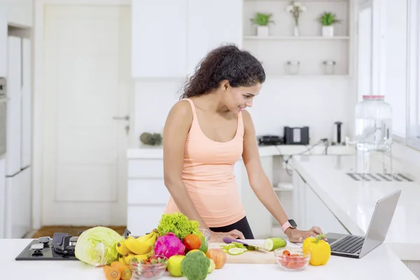 Schöne Frau auf der Suche nach Rezepten auf einem Laptop — Stockfoto