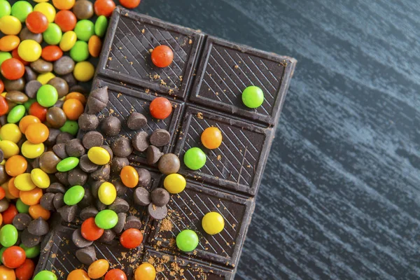 Caramelle colorate con una barretta di cioccolato sul tavolo — Foto Stock