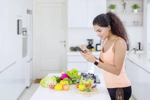 Lockigt hår kvinna söker recept på en telefon — Stockfoto