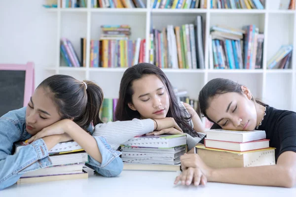 Vrouwelijke studenten slapen tijdens studie in bibliotheek — Stockfoto