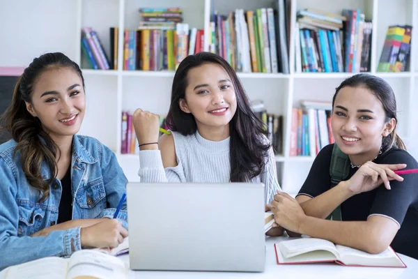 En grupp glada kvinnliga tonåringar som studerar i biblioteket — Stockfoto