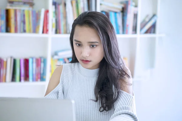 Menina bonita estudando com um laptop na biblioteca — Fotografia de Stock