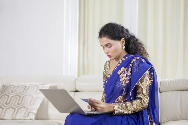 Mujer india tradicional utiliza ordenador portátil y tarjeta de crédito — Foto de Stock