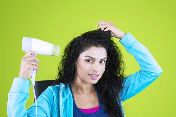 Young Indian woman using a hair dryer in the studio — Stock Photo, Image