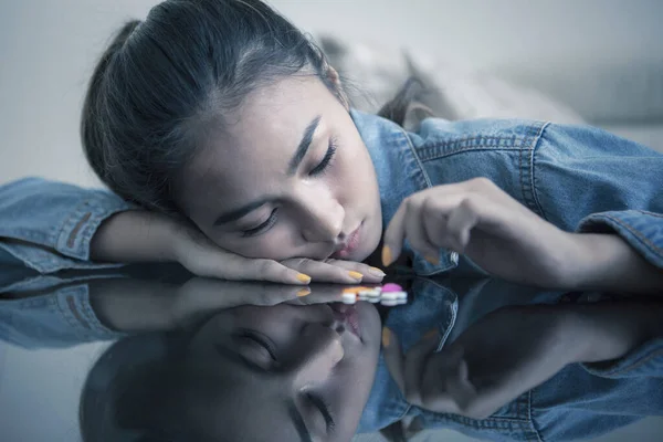 Adolescente femenina se ve triste con las drogas sobre la mesa —  Fotos de Stock