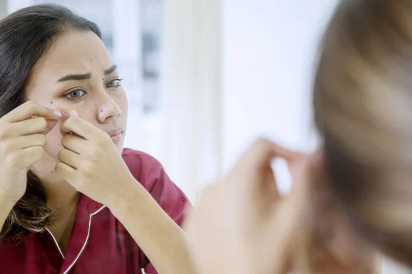 Asian teenage girl squeezing pimples on her face — Stock Photo, Image