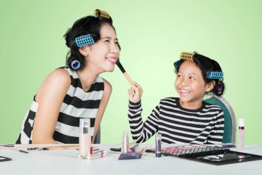 Annesinin yüzüne pudra süren mutlu çocuk. 