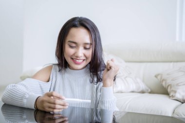 Evde hamilelik testi olan mutlu bir genç kız.