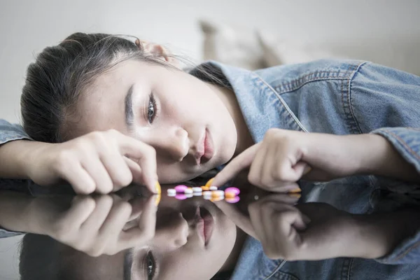 Teenage girl looks sad while counting drugs — Stock Photo, Image