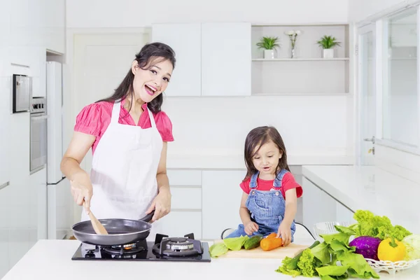 Fiatal nő főz a lányával otthon — Stock Fotó