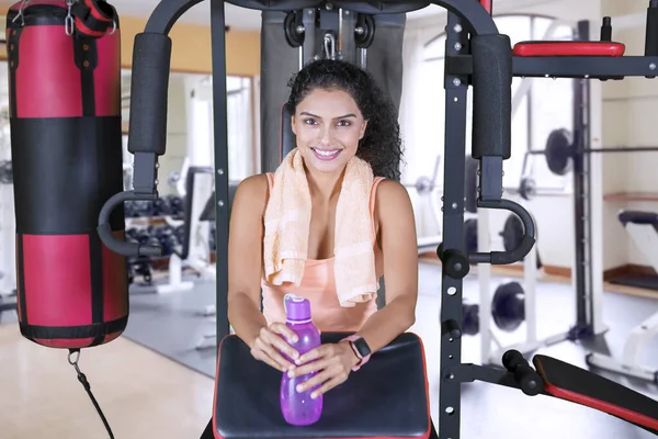Улыбающаяся женщина держит бутылку в спортзале — стоковое фото