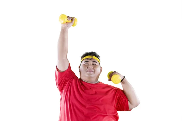 Young obese man lifting dumbbells in the studio — Stock Photo, Image