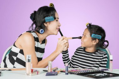 Kadın ve çocuk birbirlerine makyaj yapıyorlar.