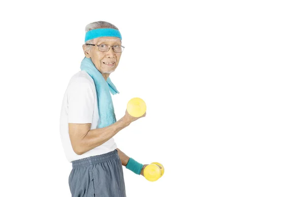 Homem sênior segurando dois halteres no estúdio — Fotografia de Stock