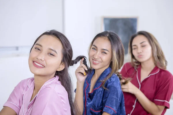 Smiling girls tying hair to each other in the bed — ストック写真