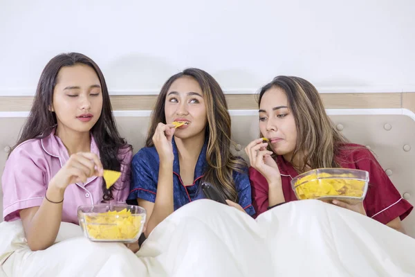 Mooie tiener meisjes genieten van chips in bed — Stockfoto