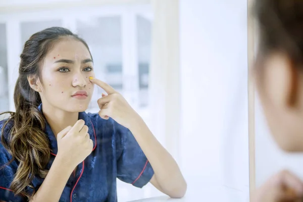 Menina adolescente bonita tocando espinhas em seu rosto — Fotografia de Stock