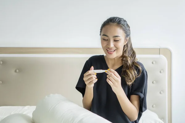 Aziatische tiener meisje kijkt gelukkig met zwangerschap test — Stockfoto