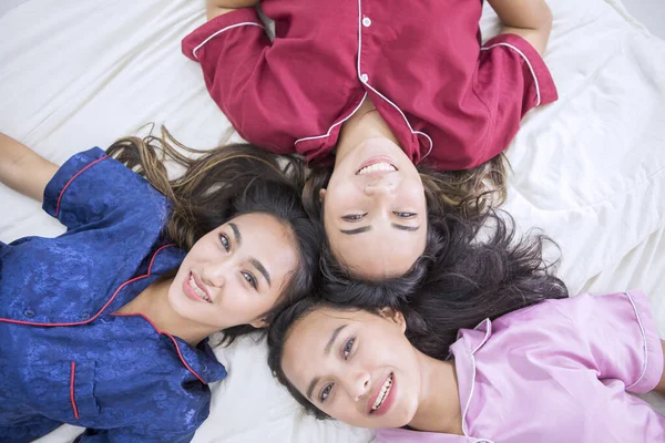 Smiling teenage girls lying on the bed — Stock Photo, Image