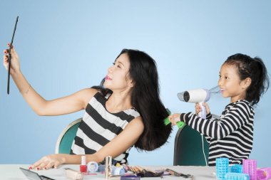 Stüdyoda annesinin saçlarını kurutan küçük kız.