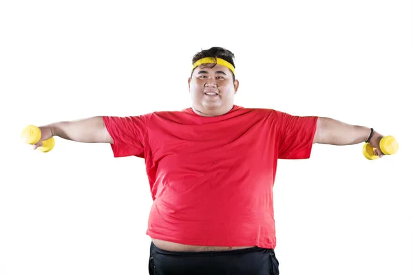 Jovem gordo segurando dois halteres no estúdio — Fotografia de Stock