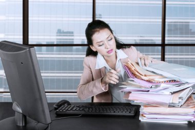 İş kadını ofiste evrak yığınlarıyla çalışıyor.