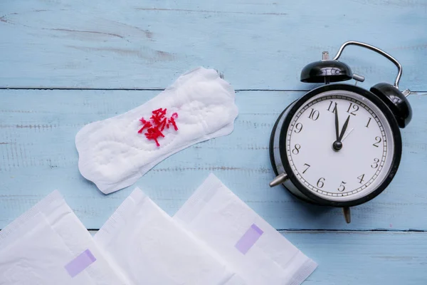 Reloj despertador con almohadilla sanitaria e hilo rojo — Foto de Stock