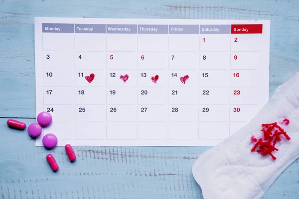 Pilule et calendrier avec tampon hygiénique sale sur la table — Photo