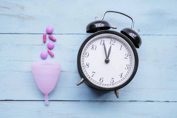 Taza sanitaria con pastillas cerca de un despertador en la mesa — Foto de Stock