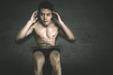 Genç adam yerde mekik egzersizi yapıyor.