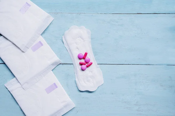 Almohadillas sanitarias con pastillas medicina sobre la mesa — Foto de Stock